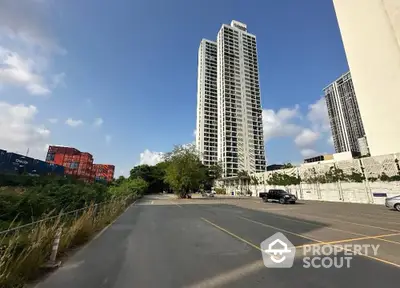 Modern high-rise building with spacious parking area and clear blue sky