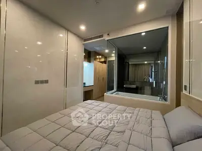 Modern bedroom with glass-walled bathroom and cozy bedding in a stylish apartment.