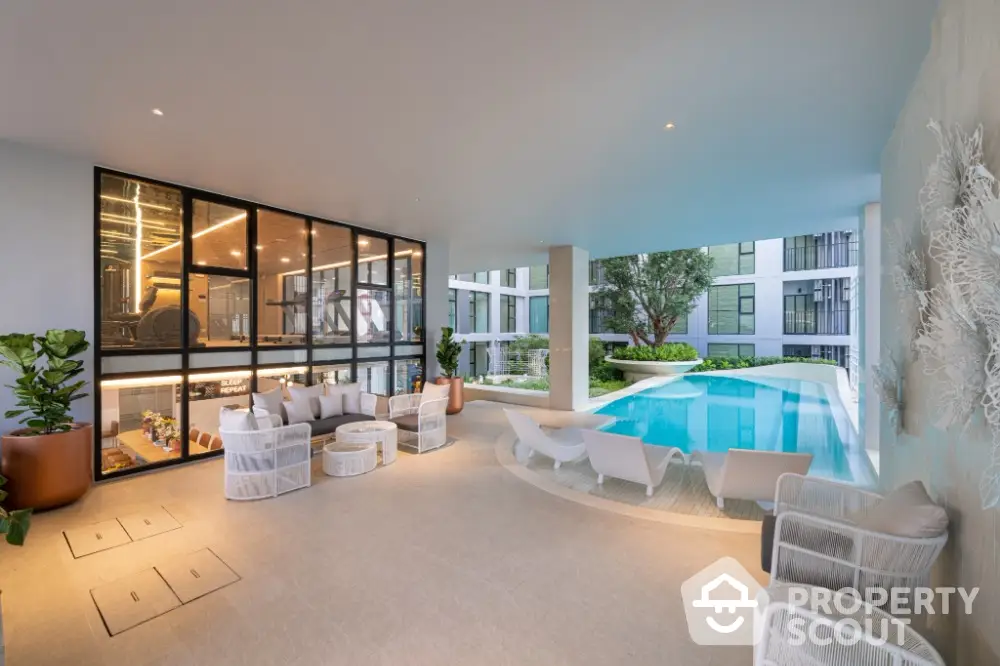 Luxurious modern poolside area with stylish seating and greenery in upscale residential complex.