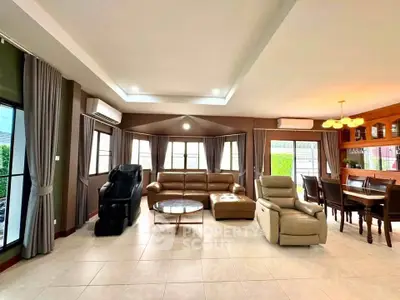 Spacious living room with modern furniture and dining area, featuring large windows and elegant lighting.