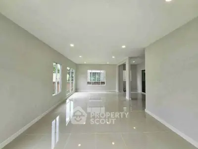 Spacious modern living room with large windows and glossy tiled floors.