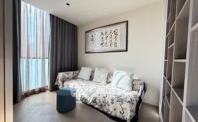 Elegant living room with stylish sofa, modern decor, and natural light through large windows.