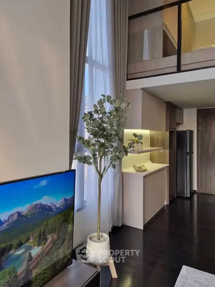 Modern living room with high ceilings and mezzanine, featuring sleek kitchen and large windows.