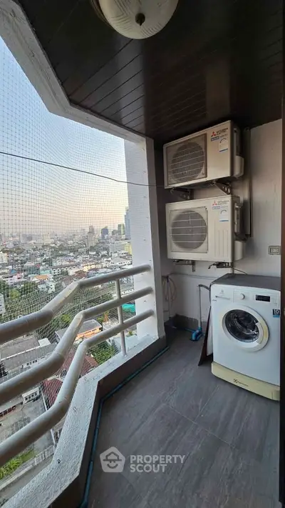 High-rise balcony with city view, featuring washing machine and air conditioning units.