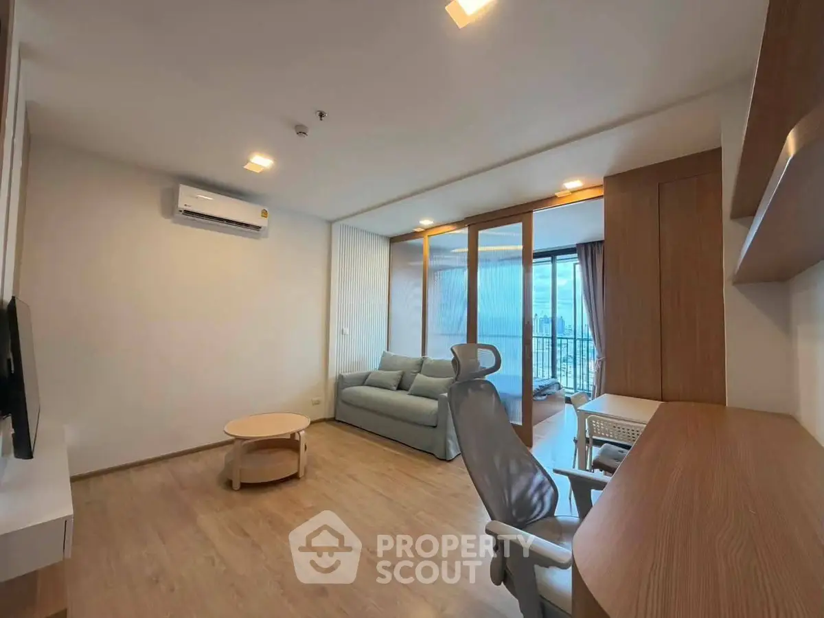 Spacious modern living room with balcony view, featuring sleek furniture and abundant natural light.