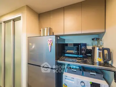 Modern kitchen with stainless steel fridge, microwave, and appliances in compact layout.
