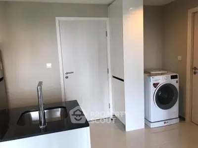Modern kitchen with sleek design and built-in washing machine, featuring black countertop and white cabinetry.