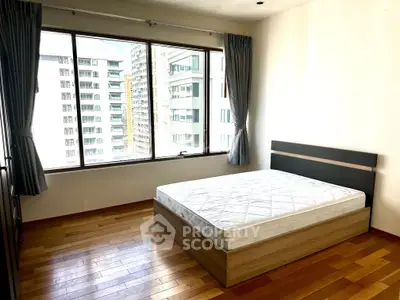Spacious bedroom with large window offering city views and natural light.