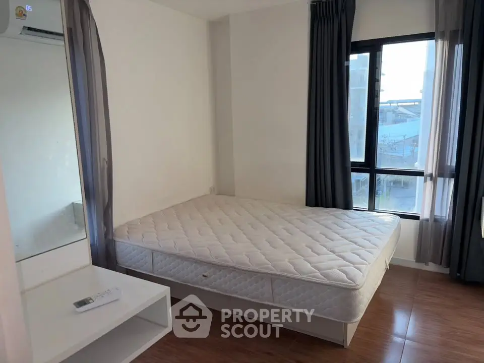 Spacious bedroom with large window and modern furnishings in a bright apartment.