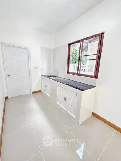 Bright and spacious kitchen with sleek countertops and large window for natural light.