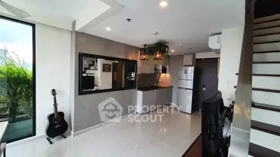 Modern open-plan living room with kitchen, featuring sleek design and natural light.