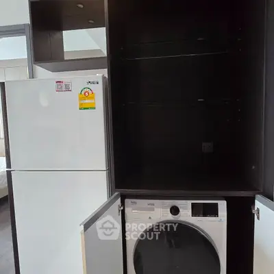 Modern kitchen with built-in washing machine and refrigerator in sleek cabinetry.