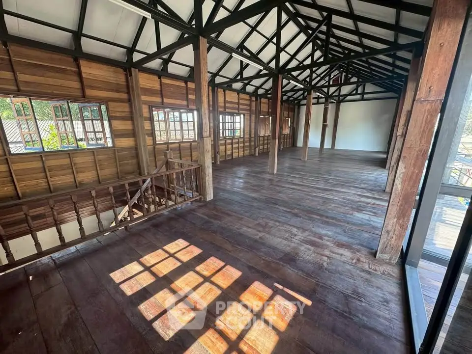 Spacious rustic interior with wooden floors and beams, perfect for creative transformation.