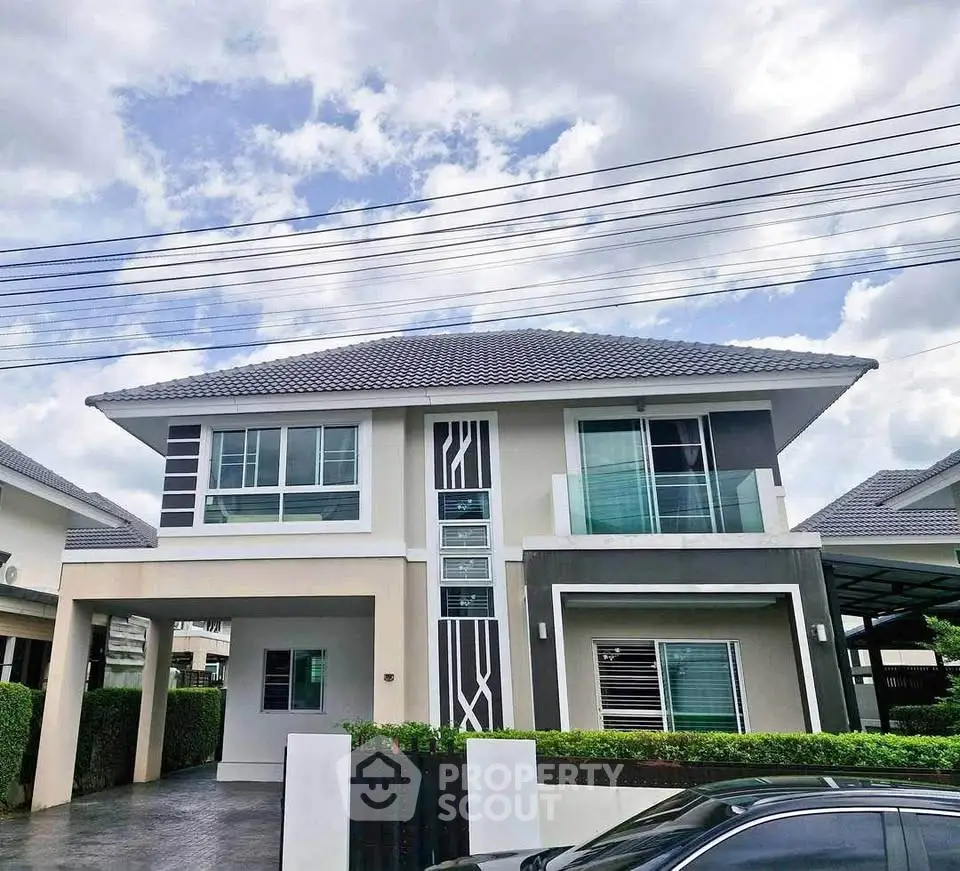 Modern two-story house with stylish facade and spacious driveway under a cloudy sky.