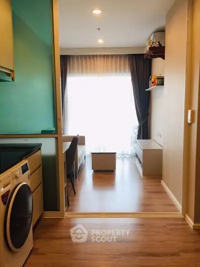 Modern living room with wooden flooring and washing machine in compact apartment