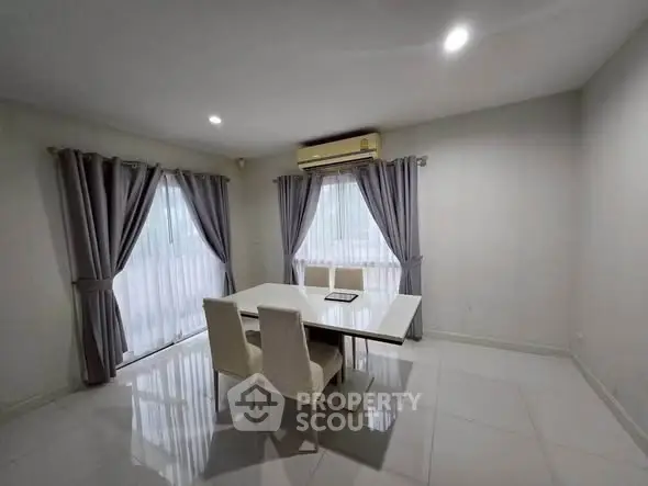 Spacious dining area with modern table and chairs, featuring large windows and elegant curtains.