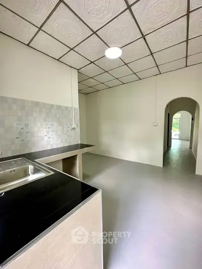 Spacious kitchen with modern design and open layout, featuring sleek countertops and tiled backsplash.
