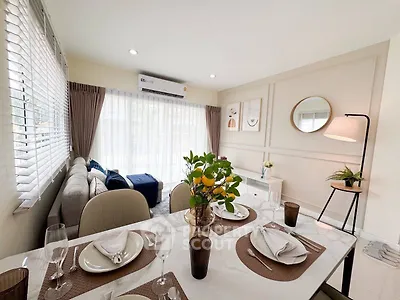 Elegant living room with dining area, featuring modern decor and abundant natural light.