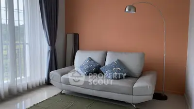 Stylish living room with modern sofa and floor lamp, featuring large windows and elegant curtains.