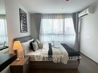 Modern bedroom with stylish decor and large window offering natural light.
