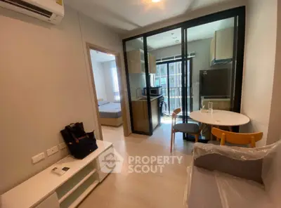 Modern apartment interior with open layout, featuring a cozy living area and a compact kitchen with glass partition.