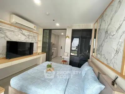 Modern bedroom with marble accents and city view, featuring a cozy bed and sleek TV setup.