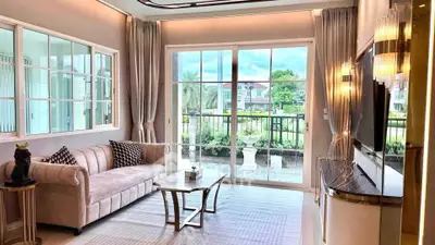 Elegant living room with large windows and stylish decor, offering a serene garden view.