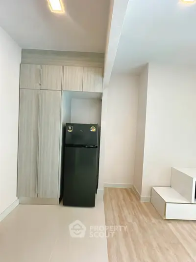 Modern kitchen with sleek cabinetry and compact fridge in minimalist apartment.