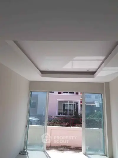Bright room with large windows and recessed ceiling, offering potential for customization.