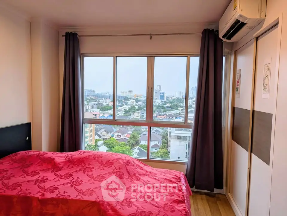 Cozy bedroom with city view and modern decor in high-rise apartment.