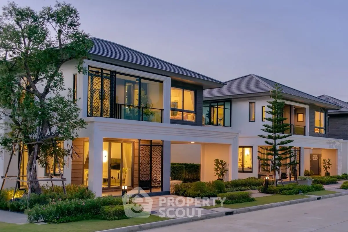 Luxurious modern two-story house with large windows and landscaped garden at dusk.