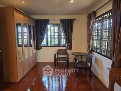 Spacious bedroom with wooden flooring and large windows for natural light.