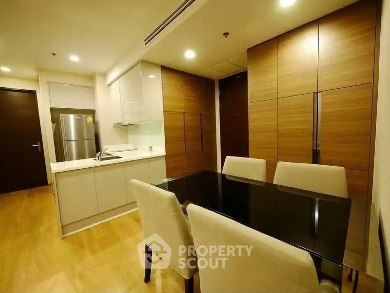 Modern dining area with sleek kitchen and elegant wooden cabinetry in a stylish apartment.
