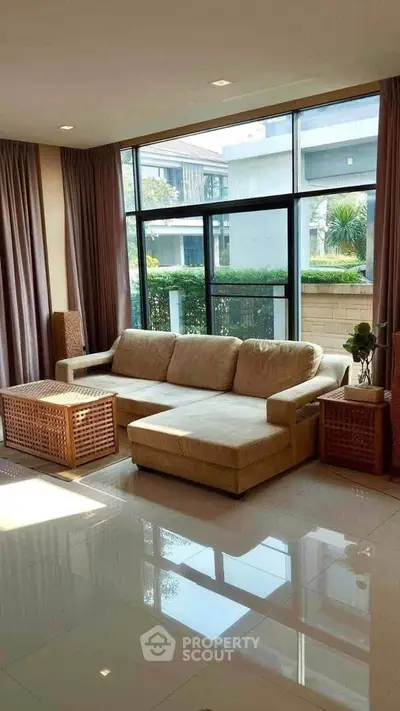Spacious living room with large windows and modern beige sofa, offering a bright and inviting atmosphere.