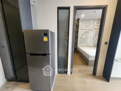 Modern apartment interior with sleek fridge and bedroom view