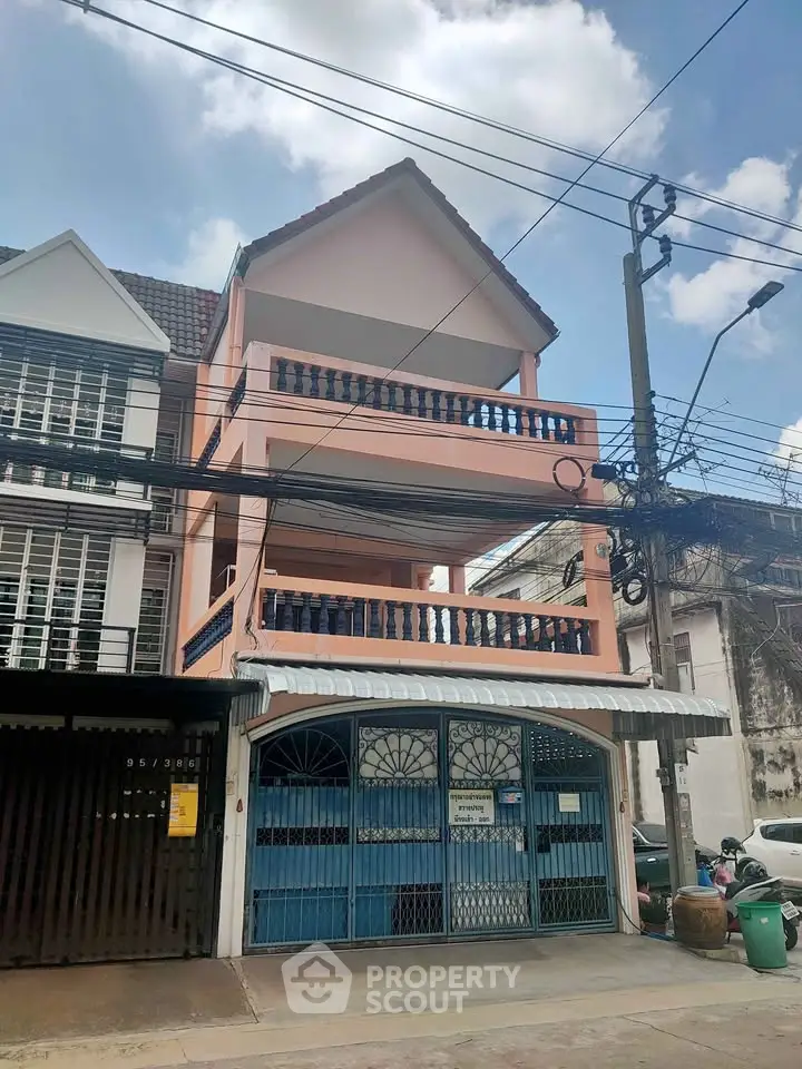 Charming three-story townhouse with unique balcony design and gated entrance.