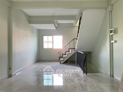 Spacious interior with modern staircase and large window, ideal for customization.