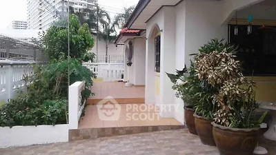 Charming exterior with lush garden and tiled patio in a serene residential area.