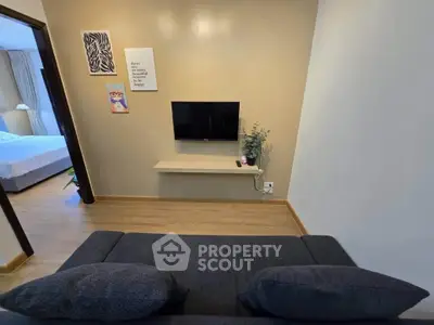 Cozy living room with modern decor and wall-mounted TV, adjacent to a stylish bedroom.