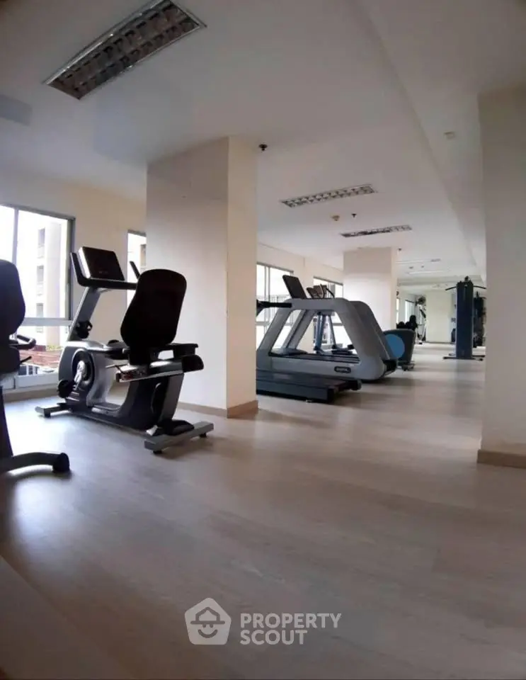 Spacious modern gym with state-of-the-art fitness equipment and large windows for natural light.