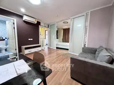 Modern apartment interior with cozy living room and visible bedroom, featuring wooden flooring and stylish decor.