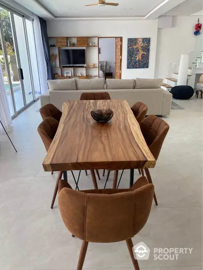 Modern dining area with wooden table and stylish chairs in open-plan living space.