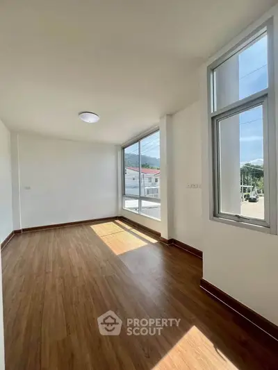 Bright and airy room with large windows and wooden flooring, perfect for a cozy living space.
