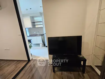 Modern apartment interior with TV and kitchen view, showcasing sleek design and open layout.