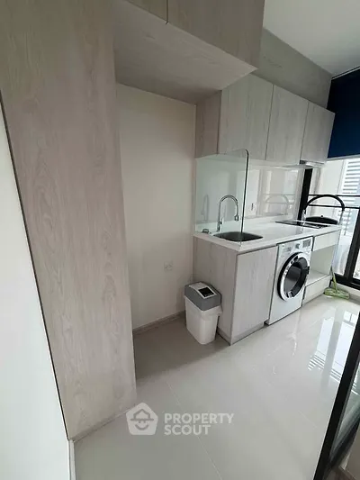 Modern kitchen with sleek cabinetry and built-in washing machine in a bright apartment.