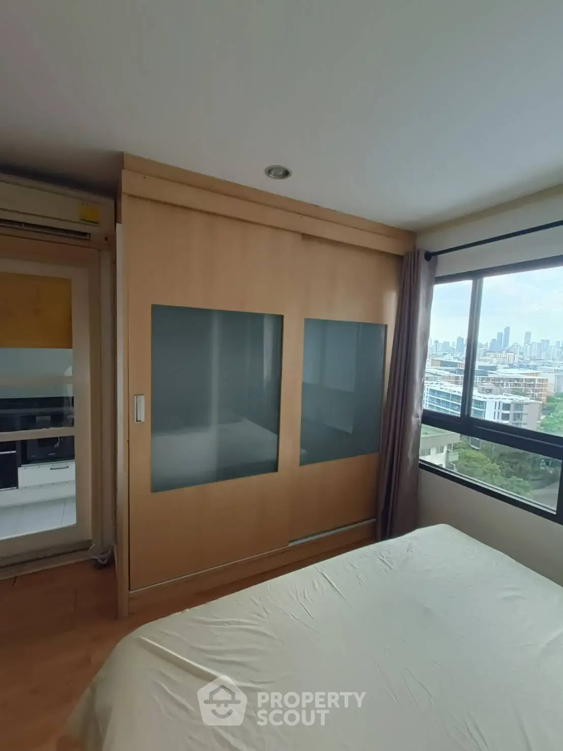 Spacious bedroom with city view and large wardrobe in modern apartment
