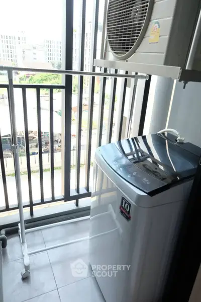Compact balcony with washing machine and air conditioning unit in modern apartment.