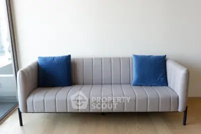 Modern minimalist living room with stylish gray sofa and blue cushions.