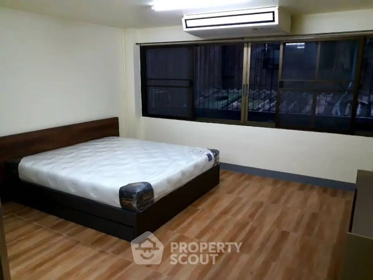 Spacious bedroom with large window and wooden flooring