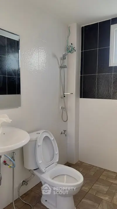 Modern bathroom with shower and toilet featuring sleek black and white tiles.